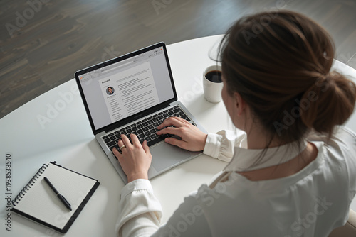 Woman typing resume on laptop applying for job
