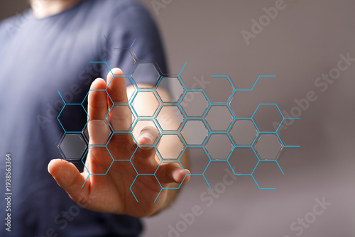 Close-up of a hand interacting with a futuristic, hexagonal interface, representing data, technology, and innovation. Pe
