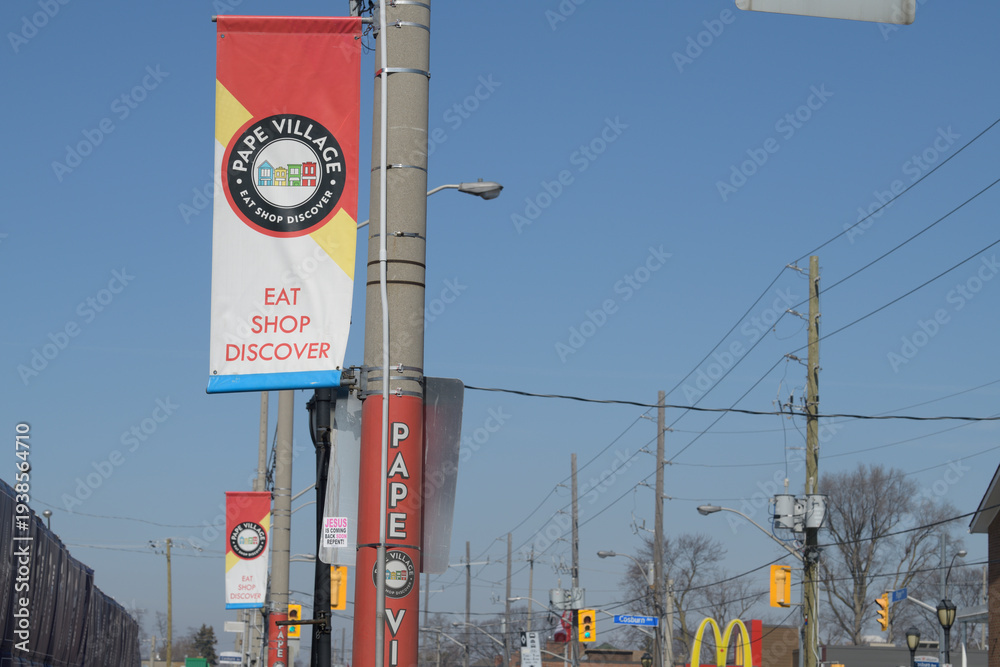 Fototapeta premium projecting banners mounted on poles at Pape Village, looking north on Pape Av, Toronto