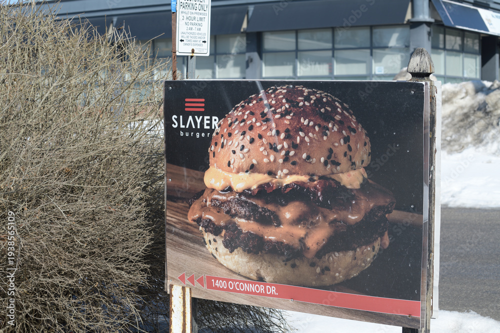 Obraz premium roadside sign featuring a big juicy burger outside Slayer Burger, a restaurant, located at 1400 O'Connor Dr, East York, Toronto