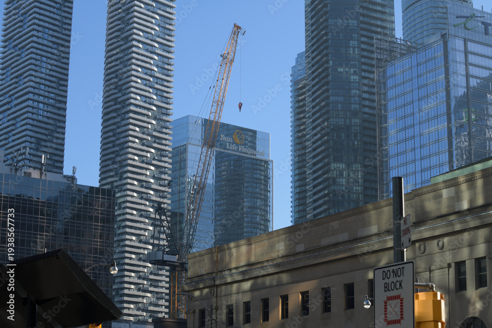 Fototapeta premium historic and contemporary towers, construction crane, and sign of Sun Life Financial from Bay and Front, Toronto