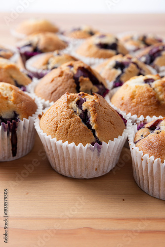 Batch of Homemade Blueberry Muffins on Light Wooden Surface.