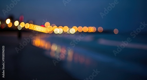 Blurry nighttime city lights by ocean.