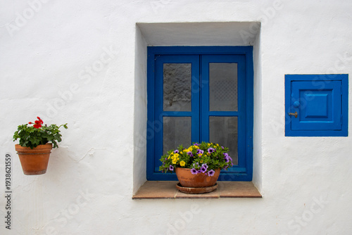 Bild auf Leinwand Traditional window with bright blue frame and colorful flower pots on a whitewashed wall in the picturesque village of Frigiliana in Andalusia, Spain
