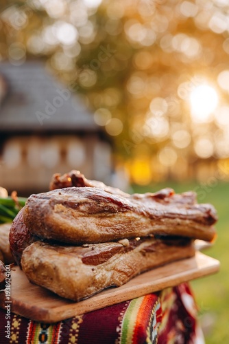 Smoked pork belly on a wooden board at an outdoor autumn picnic with warm bokeh light