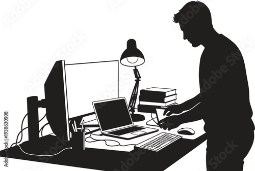 A man working on a computer in a dimly lit room with a lamp