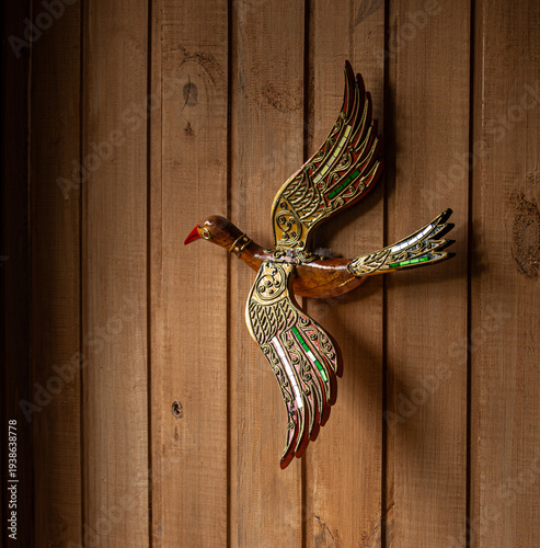 Decorative craft in the shape of a bird applied to a wooden wall.