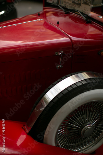 Foto Red vintage car fender closeup city, gleaming chrome wheel and rim with wire spo