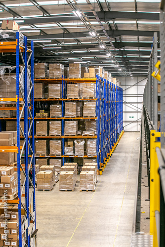 View from above of warehouse storage racks filled with pallets of cardboard boxes, showing multiple levels of industrial shelving in a logistics warehouse