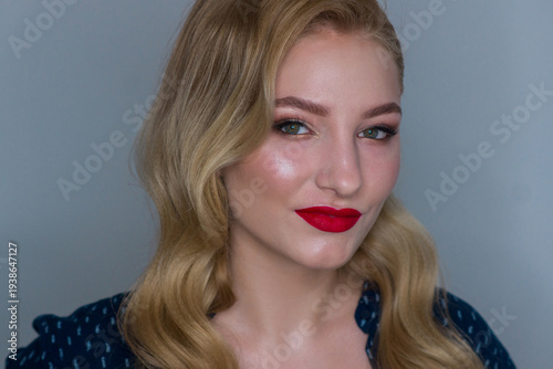 Portrait of a beautiful blonde woman with elegant wavy hair, professional makeup, and red lipstick