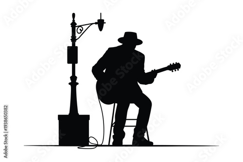 Silhouetted musician playing guitar beneath a street lamp post