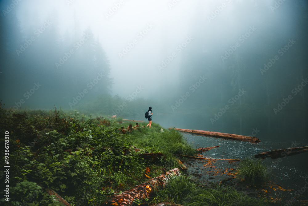 Fototapeta premium Woman Hiking Along Foggy Shore of Independence Lake in Washington State