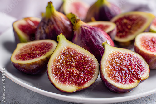 Sliced figs arranged on a plate with green leaves during daylight hours