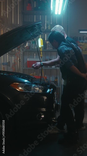 Female Technician and Male Colleague Measure Engine Oil Level Using Dipstick. Concept of Importance Regular Checks, Technical Precision, and Professional Collaboration in Workshop. Vertical Shot.