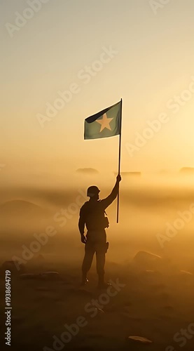 Silhouette of Soldier Holding Flag in Misty Sunrise Landscape