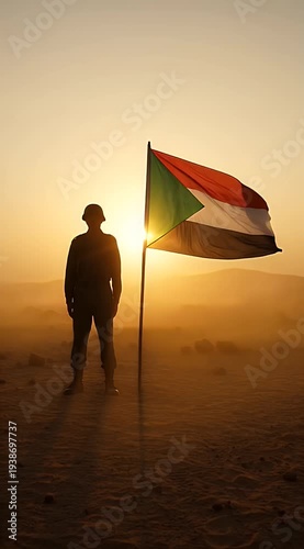 Silhouette of person standing by Sudan flag at sunset in desert