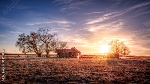 Old abandoned wooden farmhouse on the prairie at sunset. Colorful clouds float silently in the sky. 