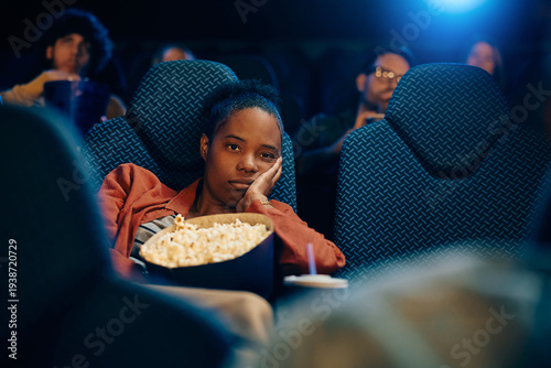 Foto Bored black woman watching movie at cinema.