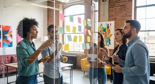 Diverse team collaborating with sticky notes on glass wall for brainstorming