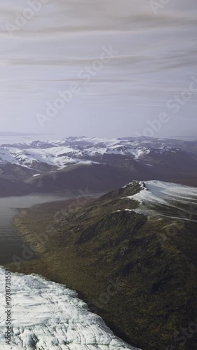 Wallpaper Mural Snow capped peaks rise above a serene valley, where a glacier meets the tranquil waters. Natures beauty unfolds in this untouched wilderness under a muted sky. Torontodigital.ca