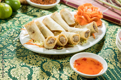 A plate of crispy fried spring rolls served with sweet dipping sauce. The festive presentation fits appetizer menus party food and Asian snack concepts.