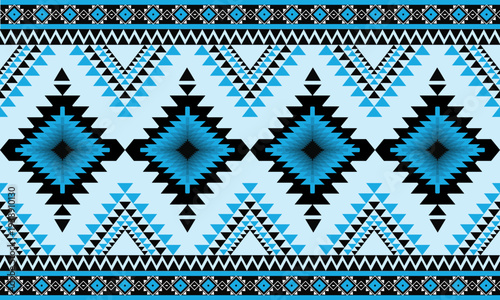 Seamless tribal geometric pattern inspired by ethnic and Aztec style design. Decorative repeating ornament with diamond shapes and zigzag elements in blue, black and white tones.