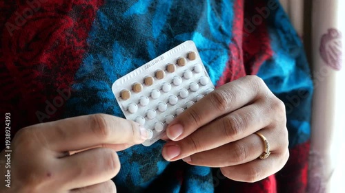 Woman holding birth control pills in her hands, close-up shot of contraceptive packaging