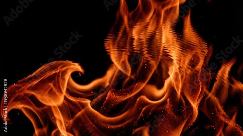 Close-up of vibrant orange flames with a shallow depth of field against a stark black background.