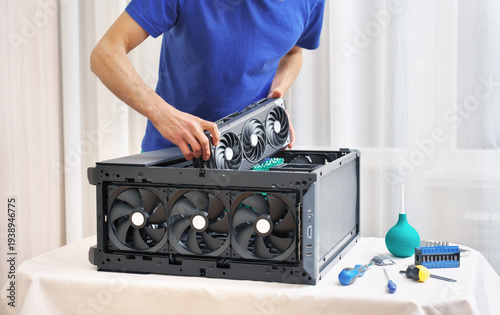 Man holding a high-end triple-fan GPU. Installing a video card into a gaming PC case.