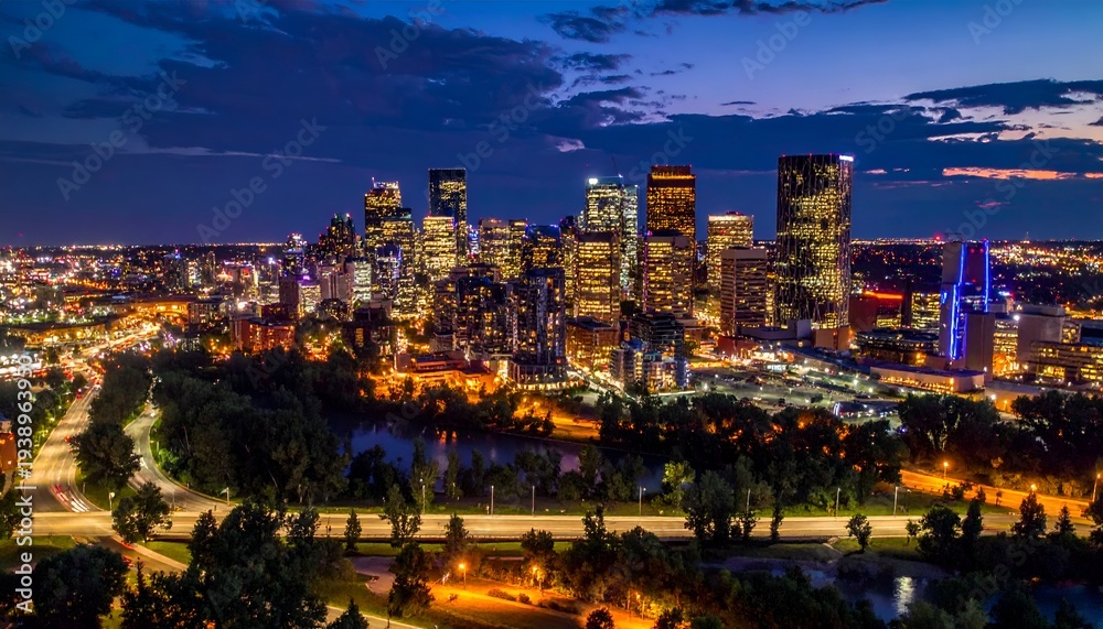 Obraz premium Illuminated city skyline at dusk with a river and highway