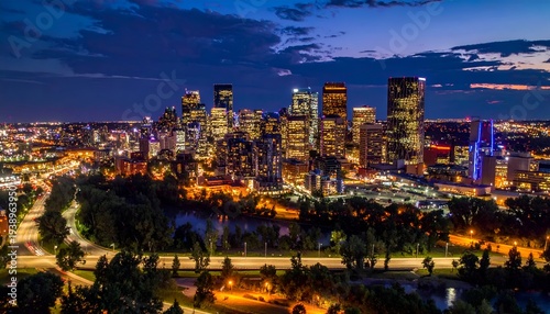 Illuminated city skyline at dusk with a river and highway