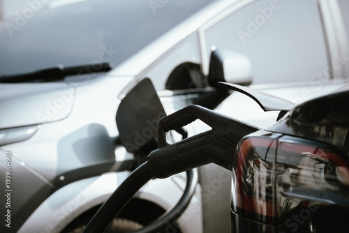 Wallpaper Mural Close-up of an electric vehicle charging with a power cable plugged into a white EV, representing clean energy, sustainable transportation, and modern green technology. Torontodigital.ca