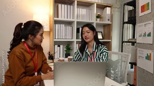 Two businesswomen discussing startup ideas and reviewing documents during a meeting in modern office, representing teamwork, business planning and collaboration in a startup company.