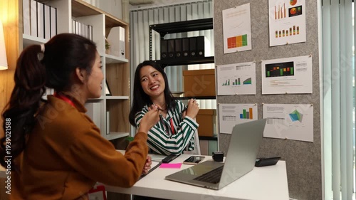 Two businesswomen discussing startup ideas and reviewing documents during a meeting in modern office, representing teamwork, business planning and collaboration in a startup company.