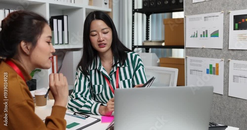 Two businesswomen discussing startup ideas and reviewing documents during a meeting in modern office, representing teamwork, business planning and collaboration in a startup company.