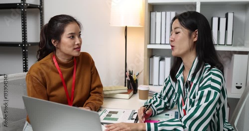 Two businesswomen discussing startup ideas and reviewing documents during a meeting in modern office, representing teamwork, business planning and collaboration in a startup company.
