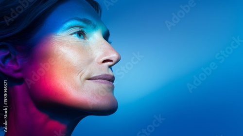 A captivating woman gazes thoughtfully, illuminated by striking blue and red lights, creating a mesmerizing play of color on her face. The atmosphere is artistic and imaginative