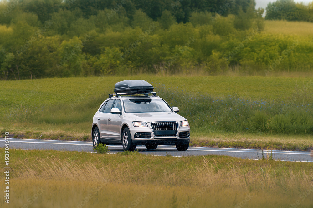 Fototapeta premium Modern White Crossover Driving with Roof Cargo Carrier