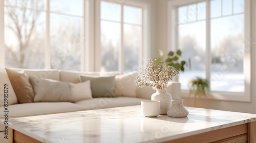 Soft sunlight fills a warm living room adorned with a cozy sofa and elegant decor. A simple table features delicate vases and dried flowers, creating a peaceful ambiance
