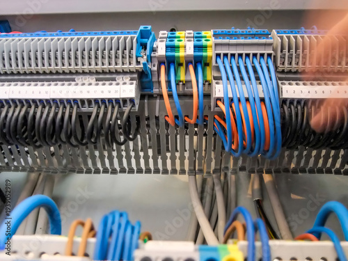 Neatly organized wiring shows black, blue, and orange wires connected to terminal blocks in an electrical panel.