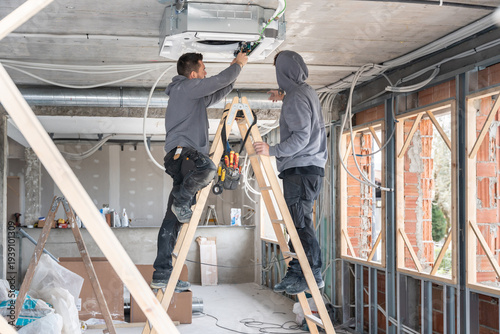 фотографія Technicians installing air conditioning unit on construction site