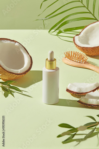 Dropper serum bottle with coconut halves and wooden brush on pastel green backdrop, organic hair oil concept with balanced minimal composition. Mockup bottle for design