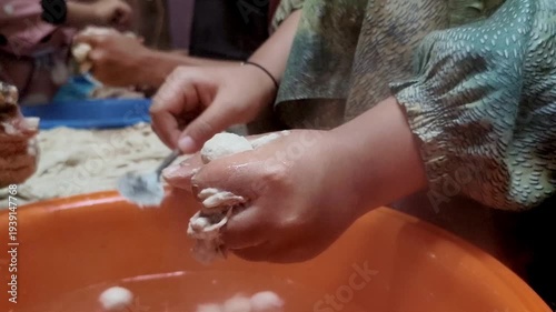 Hands shaping dough into small meatballs. 