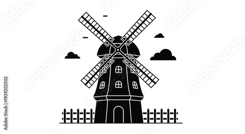 A black windmill with a picket fence under cloudy skies silhouette