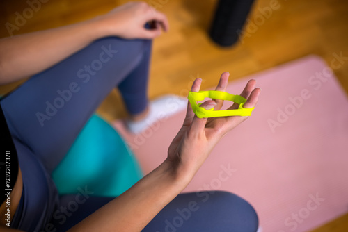 Close-up of a woman's fingers exercising with a silicone resistance band for hand strength.
