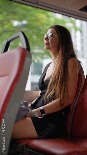Girl tourist looks out the window of a city bus on the streets of Singapore. Public transport travel in Asia.