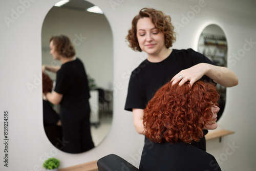 Photos Hairdresser adjusting and checking the finished curly hair volume and texture in a professional salon