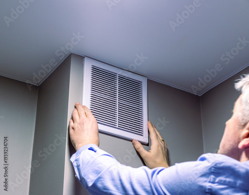 A person installing or maintaining an HVAC return air vent grille. Maintenance