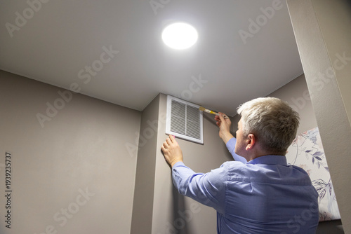 A person cleaning with a brush an HVAC return air vent grille and duct. Maintenance