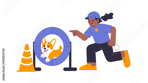 A woman coaches a happy Corgi through a dog agility hoop.